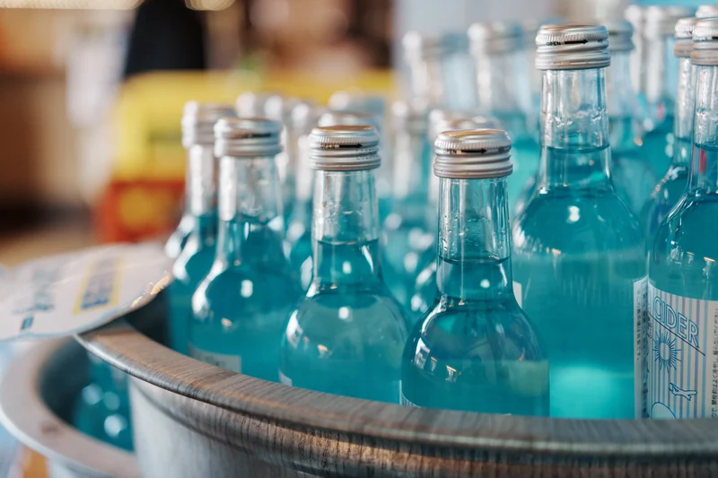 Turquoise glass bottles arranged in a shallow metal tray.