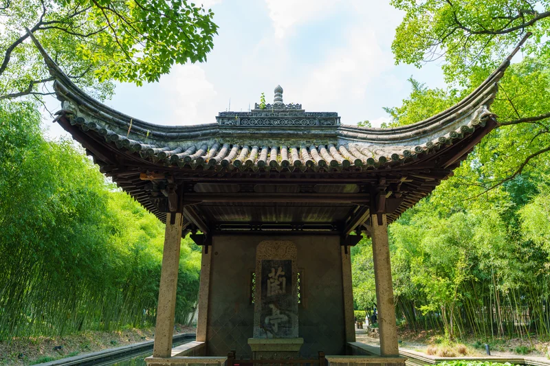 A traditional curved-roof pavilion surrounded by trees.