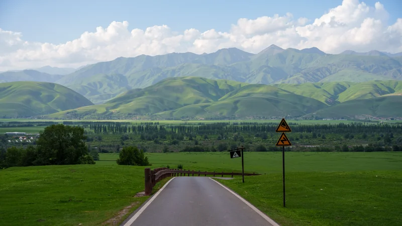 A straight road descending toward an open mountain landscape.