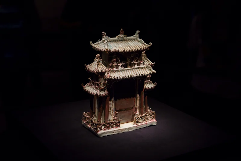 A detailed miniature traditional building lit against a dark background.